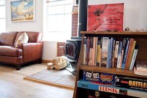 Ein Wohnzimmer mit einem braunen Ledersofa, einem Kamin, einem Bücherregal mit verschiedenen Büchern und einem Gemälde an der Wand.