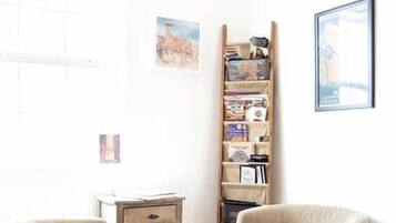 A room with two chairs, a bookshelf, a small table, and a rug.