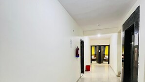 Un couloir propre et bien éclairé, avec des murs blancs et un sol carrelé, qui mène à plusieurs portes.