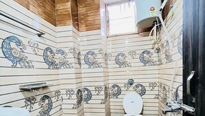 Une salle de bain avec des carreaux décorés, des toilettes, un lavabo et un seau.