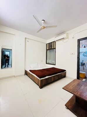 Ein Schlafzimmer mit Bett, Deckenventilator, Fenster und Klimaanlage.