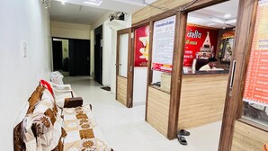 Un hall d’hôtel comprenant un comptoir d’accueil, un espace d’attente avec un canapé et un couloir menant aux autres chambres.