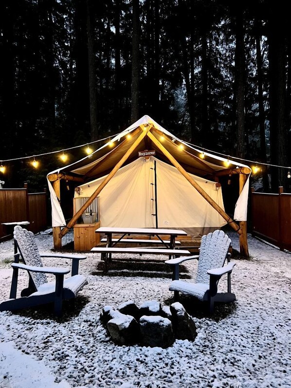 A tent with a table and chairs in a snowy outdoor setting.