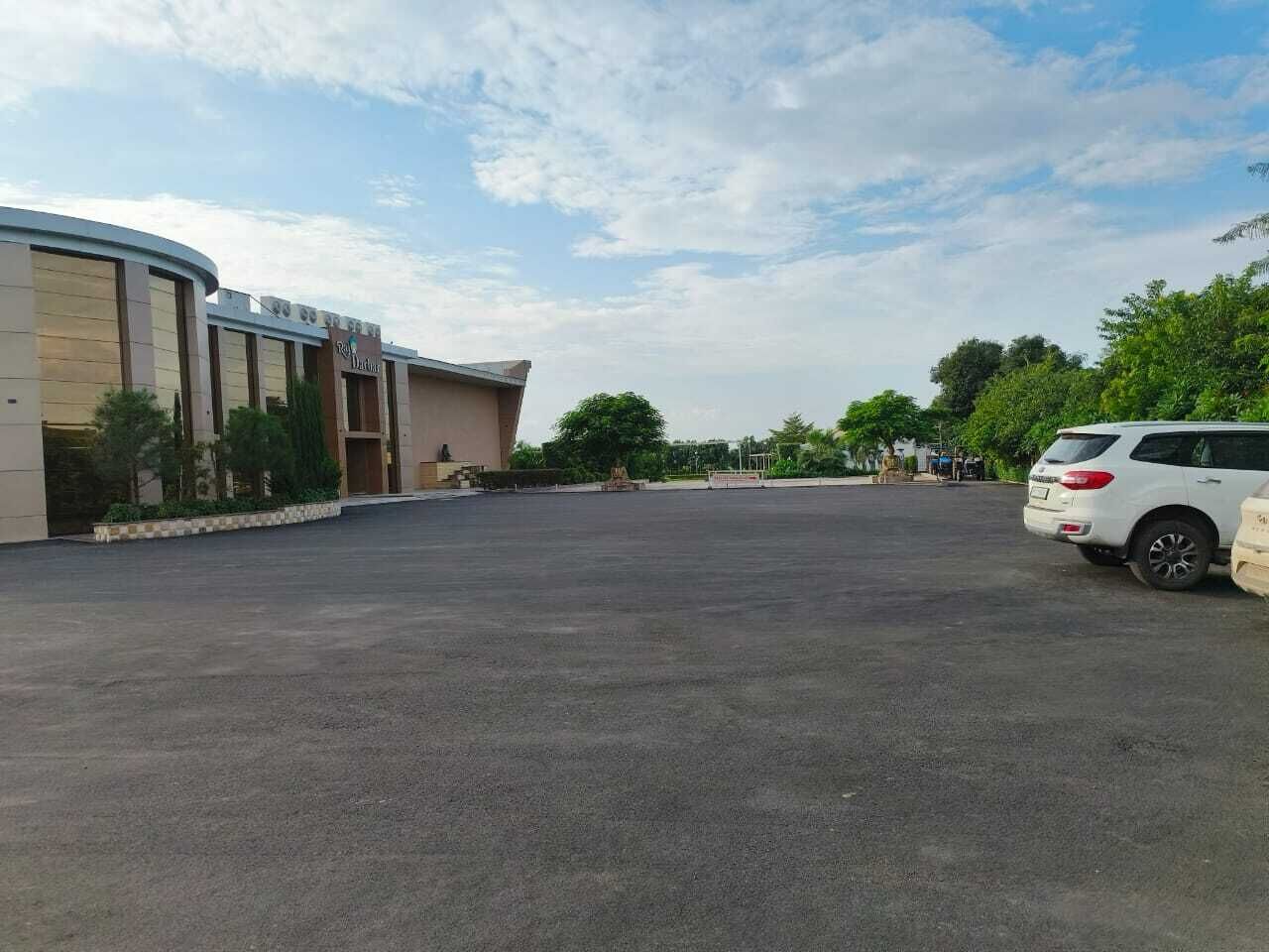 A parking lot with a building labeled "Riviera D'Azur" and a white SUV parked on the right.