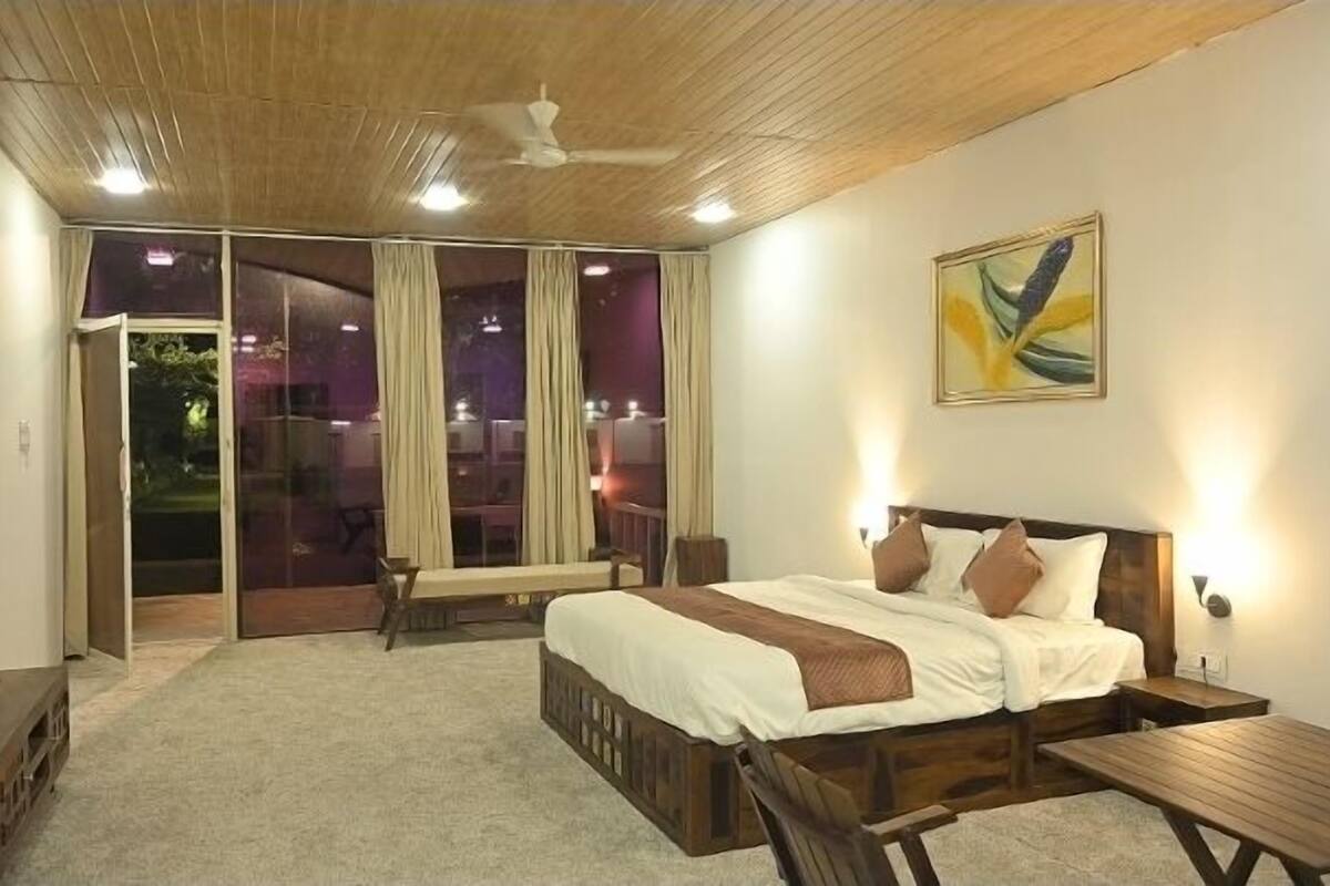 Ein Schlafzimmer mit Bett, Schreibtisch, Sessel, Fernseher und Deckenventilator.
