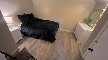 A bedroom with a bed, a nightstand, a chair, and a dresser.