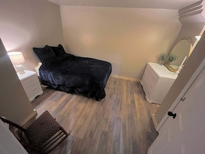A bedroom with a bed, a nightstand, a chair, and a dresser.