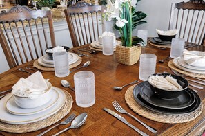 A dining table set with plates, bowls, cutlery, and glassware, surrounded by chairs. - Hot Tub Haven Yard Swing Set BBQ Games Desk WiFi (San Antonio)