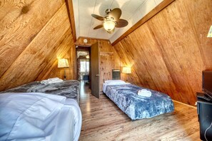 A room with two beds, wooden walls, a ceiling fan, and a television. - Cozy Getaways in this Cute A-Frame Cabin in Suches, Georgia (Suches)