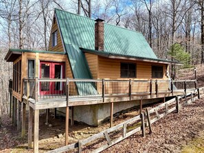 A cabin with a green roof, a red door, and a wooden deck. - Cozy Getaways in this Cute A-Frame Cabin in Suches, Georgia (Suches)