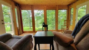 A wooden cabin interior with a sofa, a table, and a chair. - Cozy Getaways in this Cute A-Frame Cabin in Suches, Georgia (Suches)