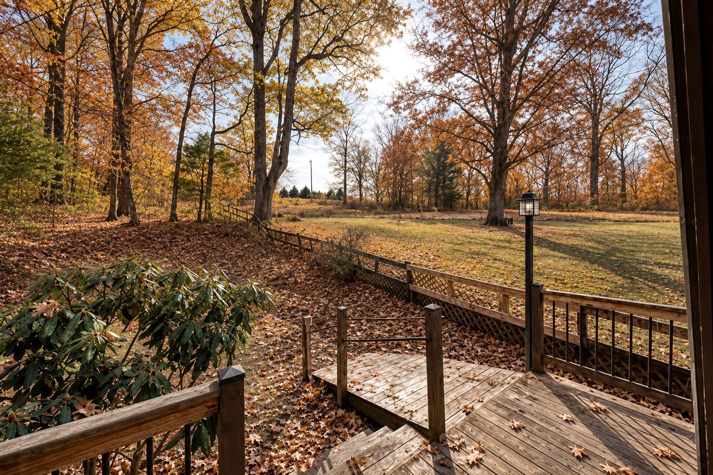 A wooden deck with a view of a park with trees and a fence.