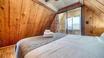 A bedroom with a bed, a small table, and a chair.