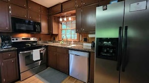 A kitchen with wooden cabinets, stainless steel appliances, a built-in microwave, and a refrigerator.