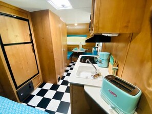 A compact kitchen with a checkered floor, a sink, a toaster, and wooden cabinets.