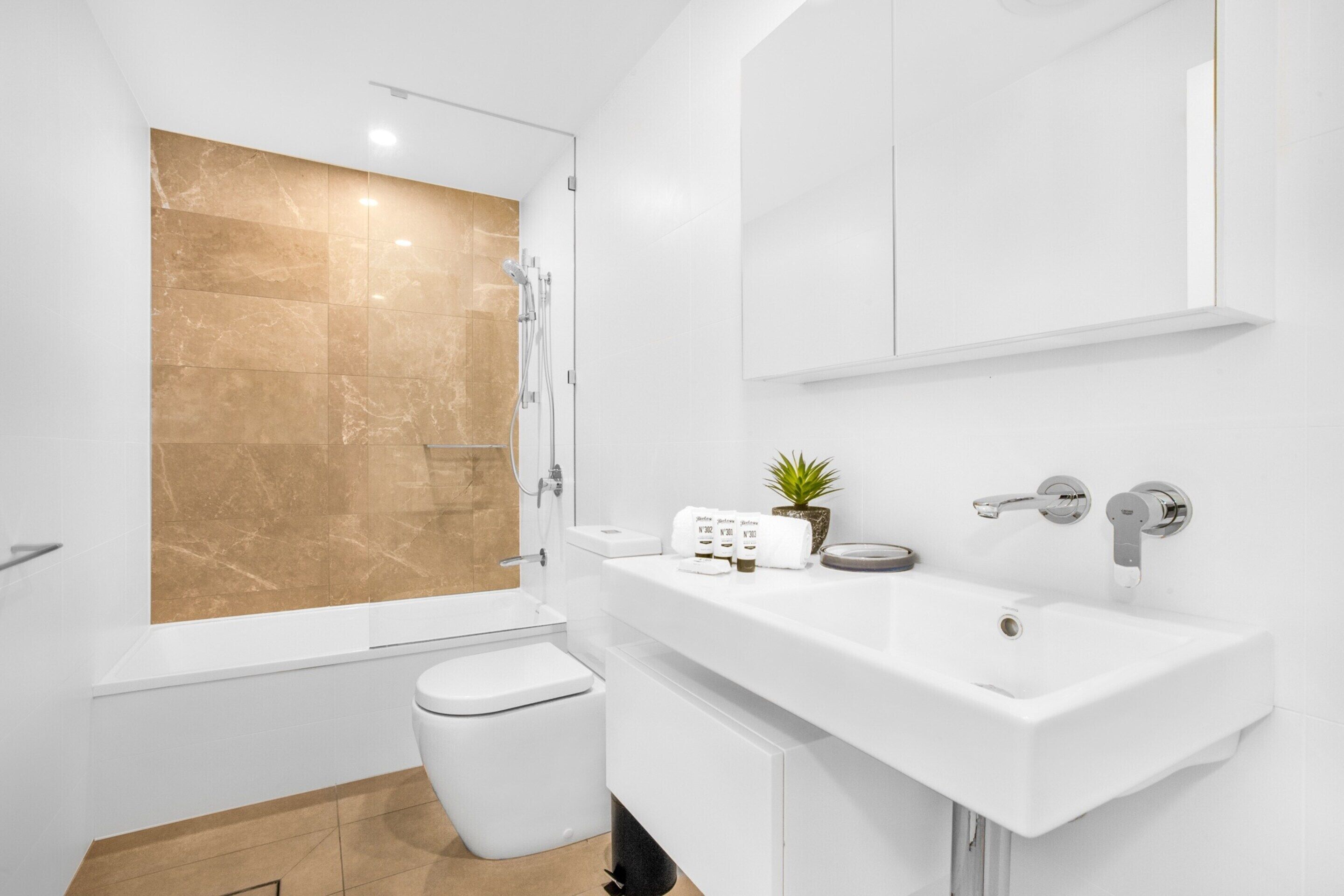 Ein modernes Badezimmer mit Badewanne, Toilette, Waschbecken und Spiegel.