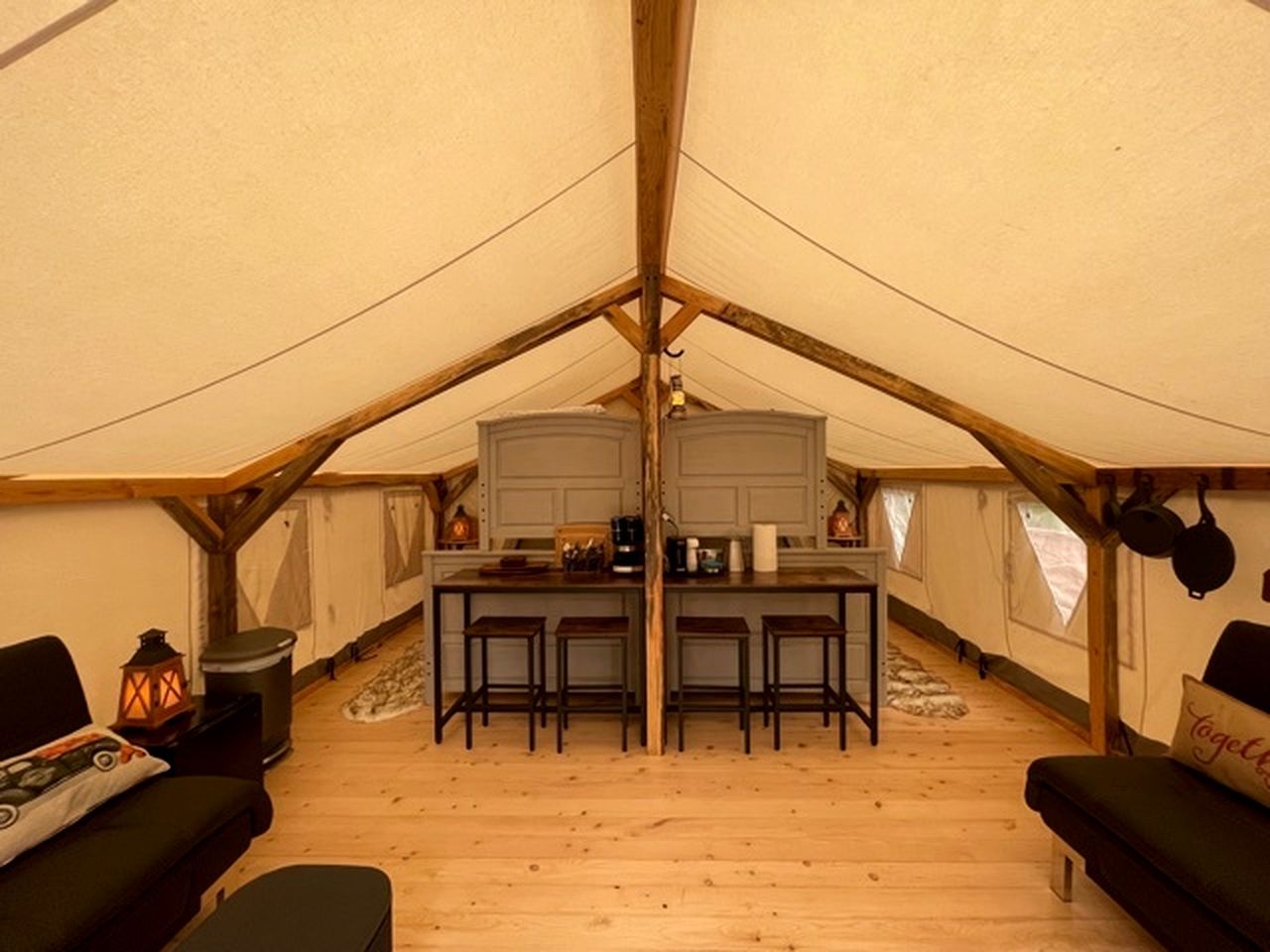 A tent with a central kitchen area, wooden flooring, and seating arrangements.