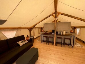 A tent with a kitchenette, a sofa, and a small table.