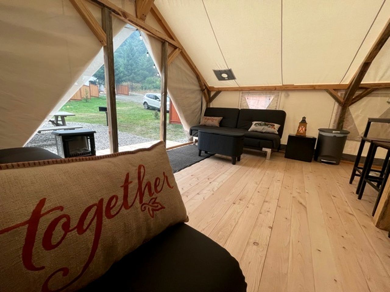 A tented accommodation with a sofa, a small table, and a bench.