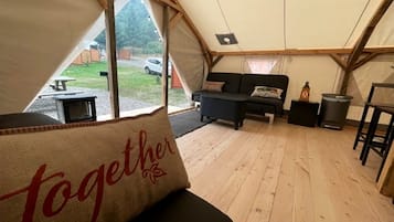 A tented accommodation with a sofa, a small table, and a bench.