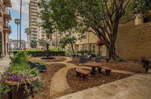An outdoor courtyard with a central fountain, surrounded by seating areas and lush landscaping. - Ocean-View 1BR Condo in Historic Cooper Arms (Long Beach)