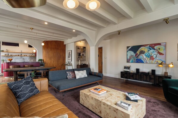A spacious living area with a sofa, coffee table, and a kitchen in the background.