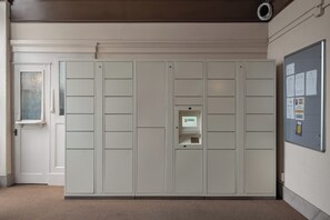A room with a large wardrobe, a small desk with a computer, and a bulletin board on the wall.