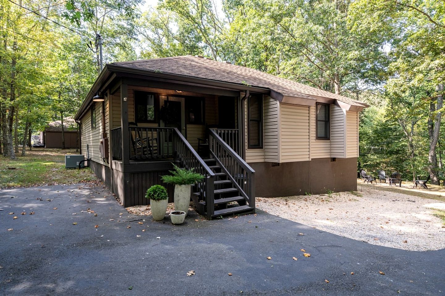 A small cabin with a porch, a staircase, and a driveway.