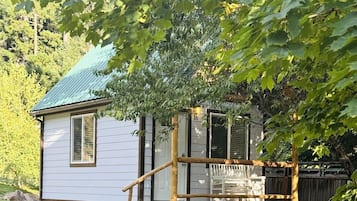 Une petite cabane avec un porche, une terrasse en bois et un panneau indiquant son emplacement.