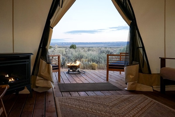 A cozy room with a fireplace, a small fire pit, and a view of the landscape.