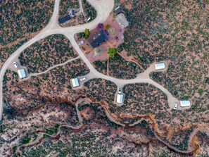 Una vista aerea di una proprietà con diversi edifici, strade tortuose e vegetazione rada.