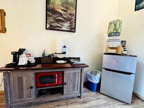 Una kitchenette equipada con microondas, un refrigerador pequeño, un lavabo y un bote de basura.