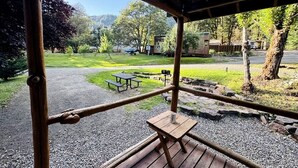 Une terrasse en bois avec des tables de pique-nique et une vue sur un parc et des montagnes.