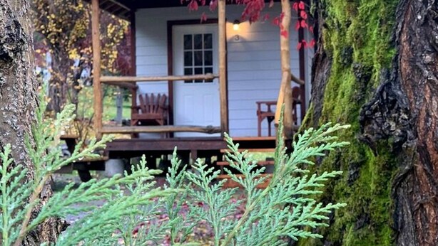 Une cabane avec une véranda en bois, une porte et une petite fenêtre.