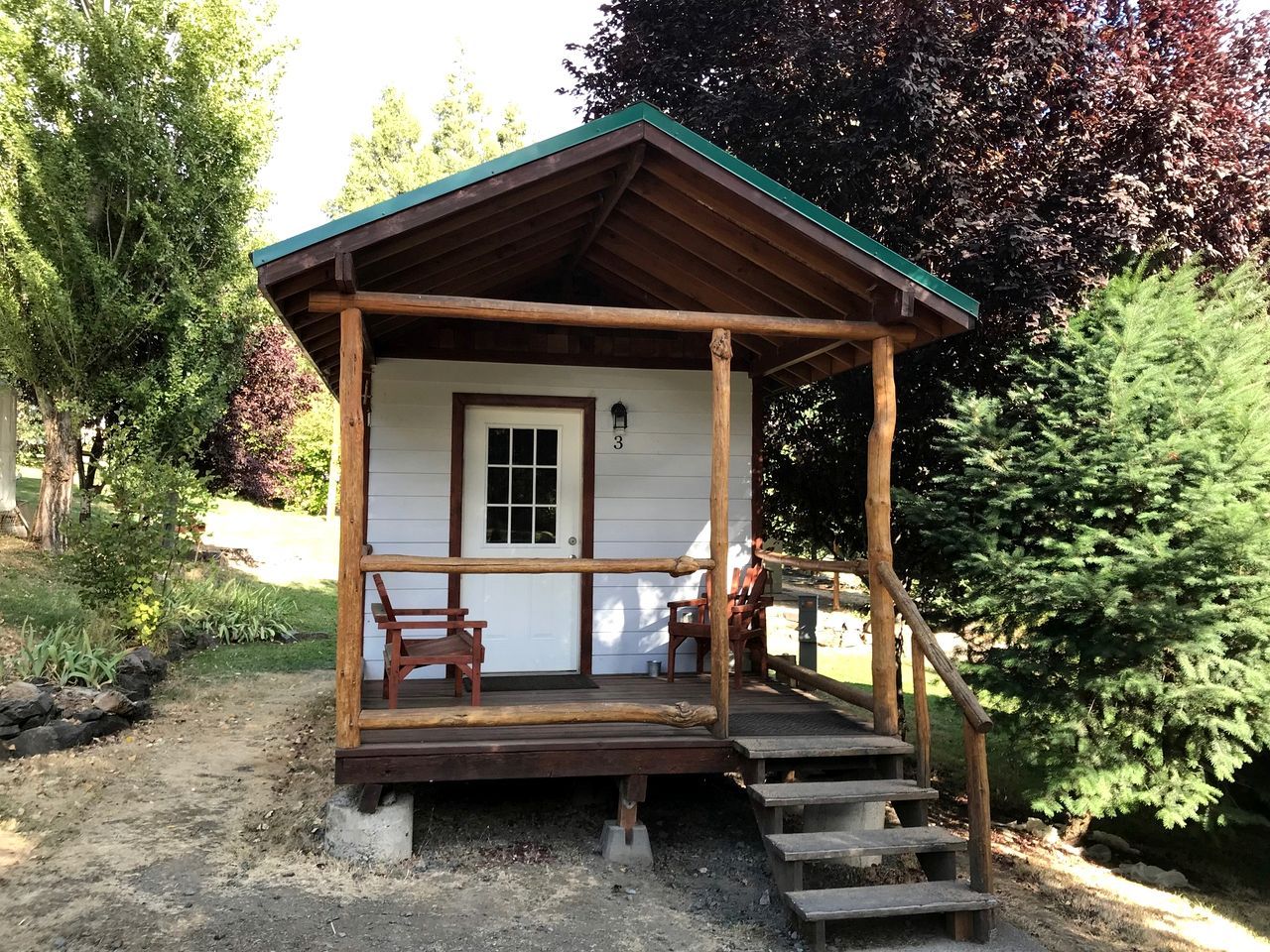 A wooden cabin with a porch, a door, and a window.