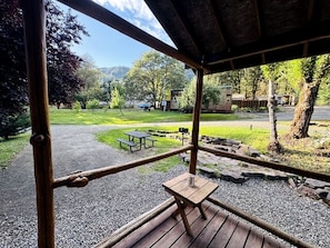 A wooden deck with picnic tables and a view of a park and mountains.