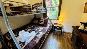 Une chambre avec un lit superposé, une fenêtre, une table de chevet et une lampe.