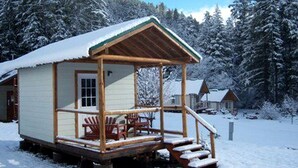 Une cabane en bois avec une véranda, une table et des chaises.