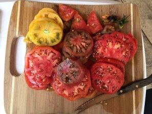 Ein Holzschnittbrett mit unterschiedlich geschnittenen Tomaten und einem Messer.