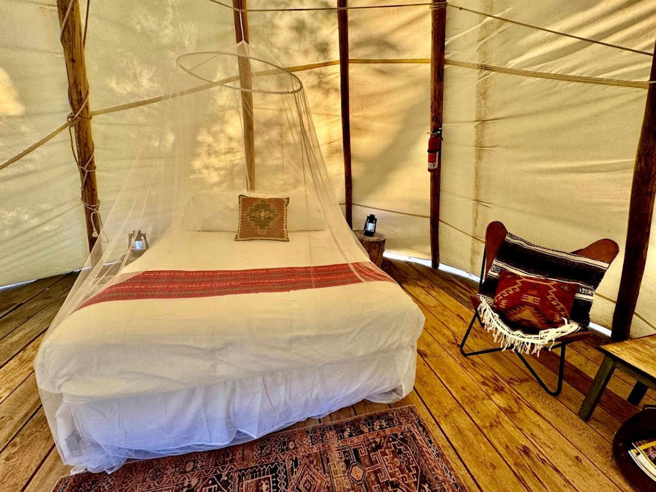 Una carpa con una cama, una silla y una mesita.