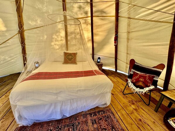 Ein Zelt mit einem Bett, einem Stuhl und einem kleinen Tisch.