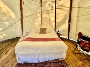 Una cama con dosel en un espacio que recuerda a una tienda.