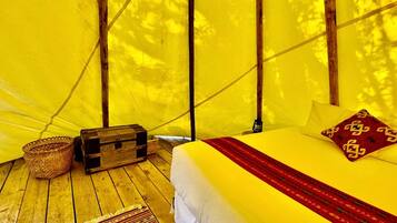 Una carpa con una cama, una cesta tejida y un baúl de madera.