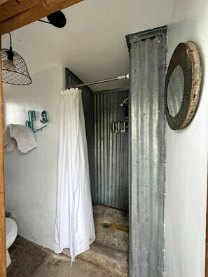 Un baño con ducha, inodoro, toallero y espejo.