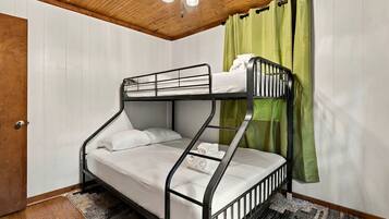 Un lit superposé avec un plafond en bois et un rideau vert.
