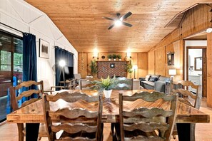Un área de comedor con una mesa y sillas de madera, una chimenea de ladrillo y un ventilador de techo.