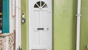 Une porte blanche portant le numéro 79, une petite fenêtre au-dessus, et une boîte aux lettres sur le côté gauche.