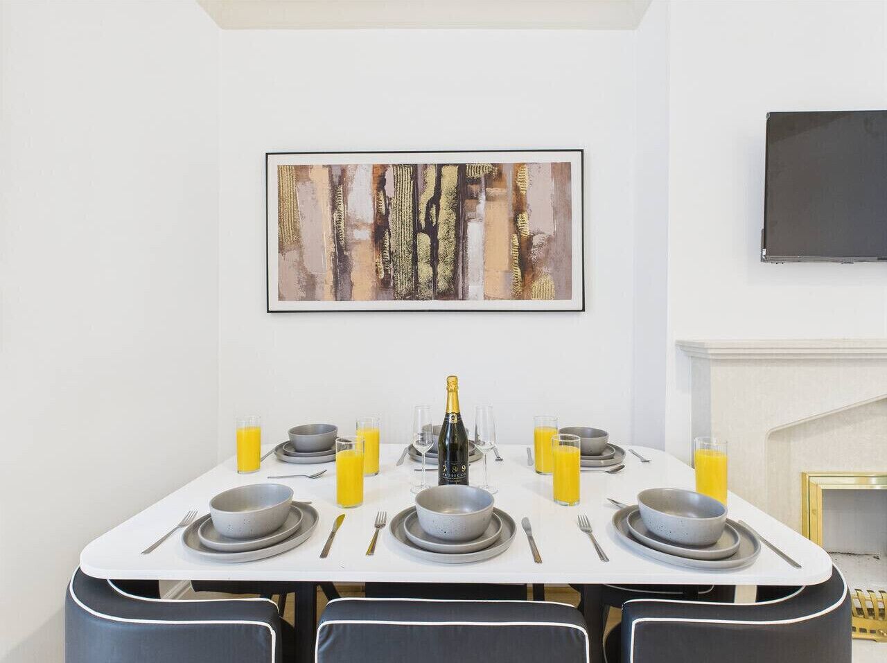 A dining table set with plates, bowls, glasses, and a bottle of champagne.