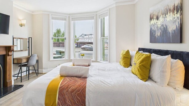 Ein modernes Schlafzimmer mit einem großen Bett, einem Schreibtisch und Blick ins Freie.