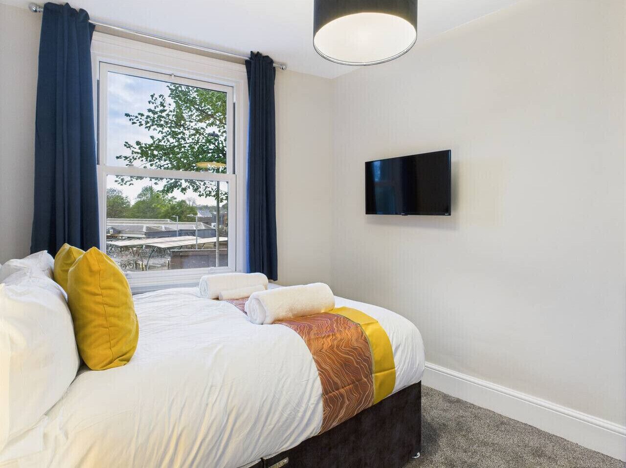 Een hotelkamer met een bed, een flatscreen televisie en een raam met gordijnen.
